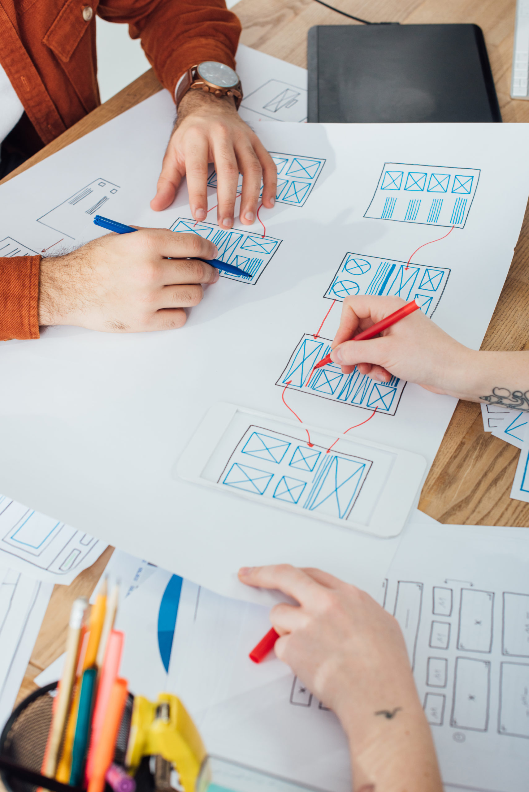 Cropped view of ux designers working with layouts and sketches on table